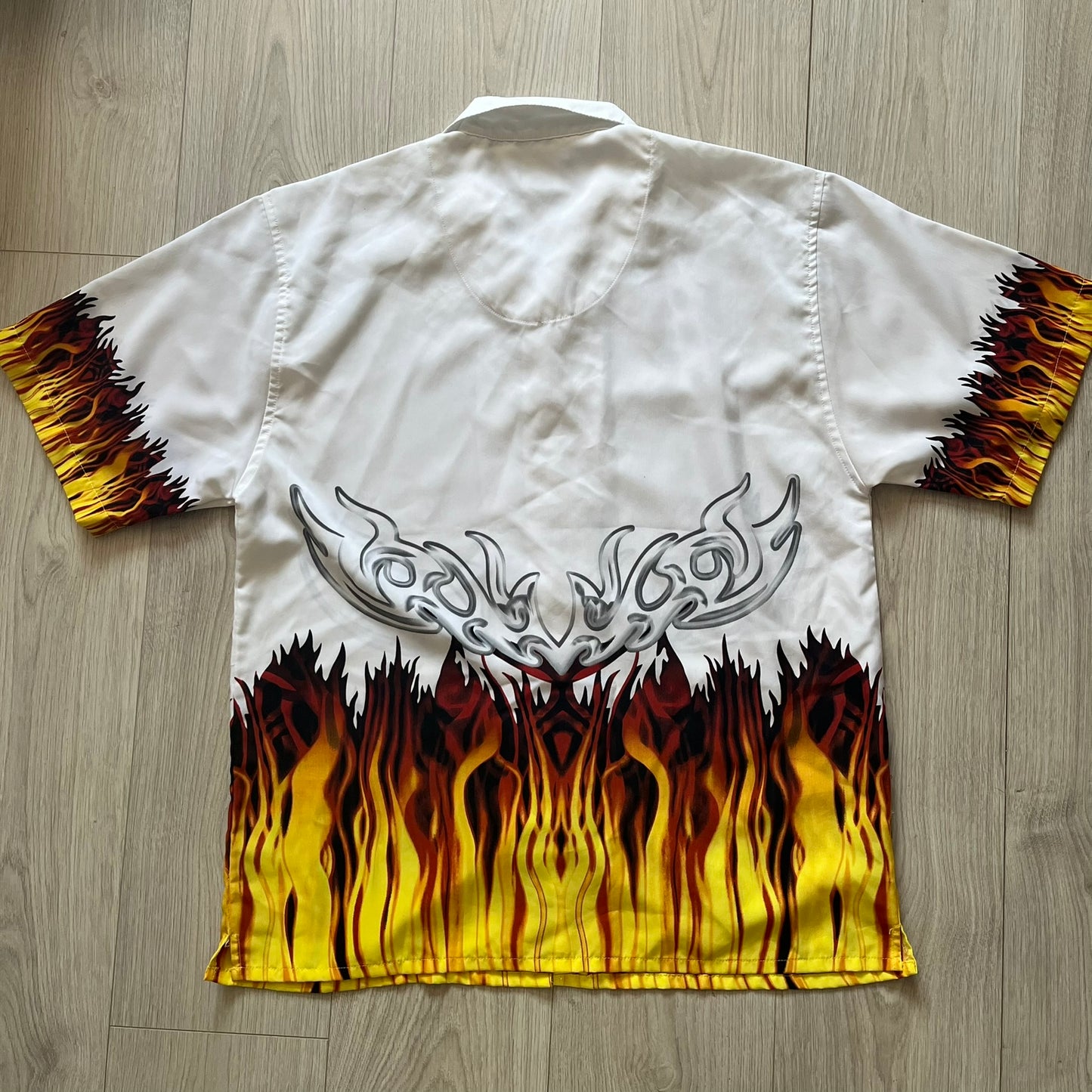 White shirt with flame and tribal design on a wooden floor