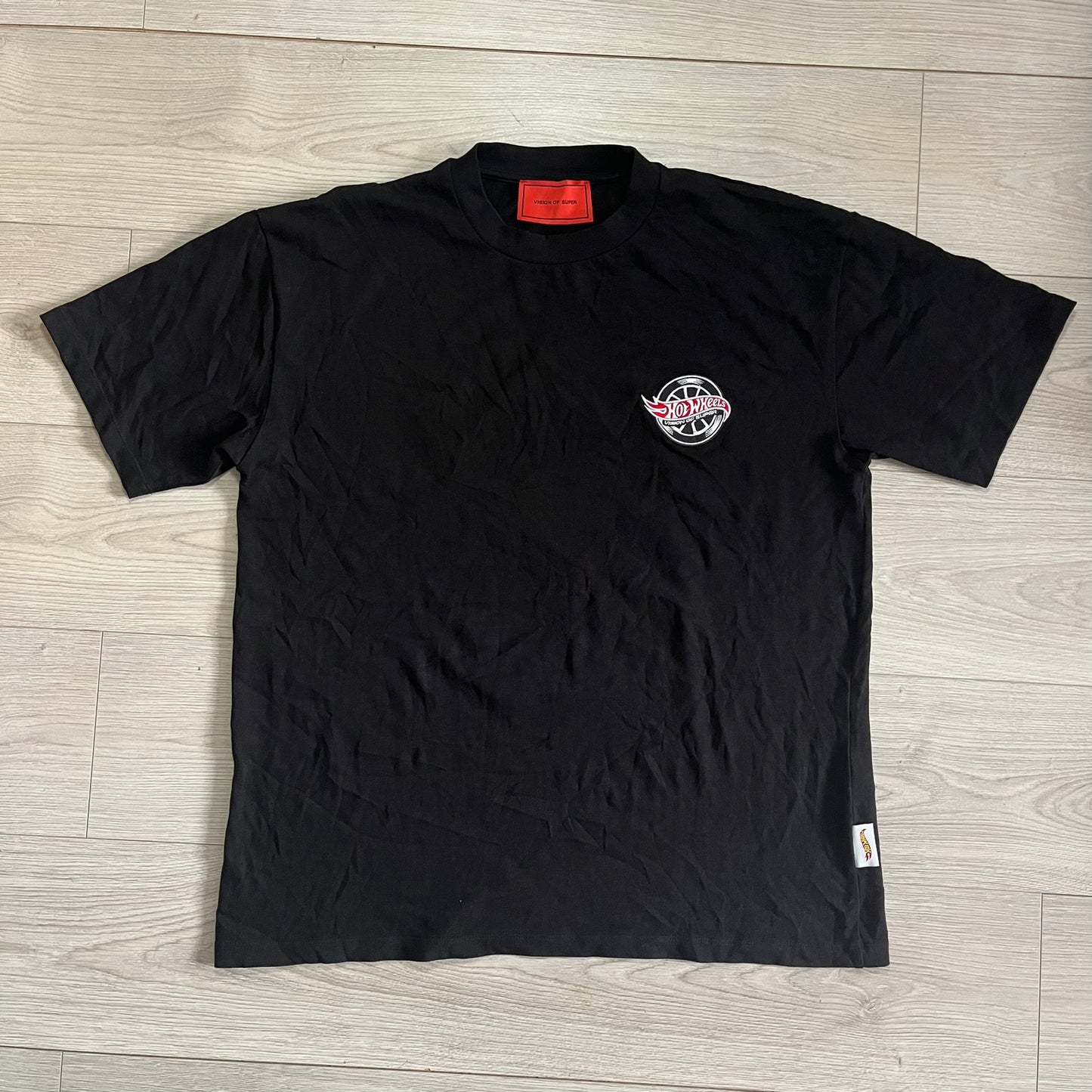Black t-shirt with a logo on a wooden floor