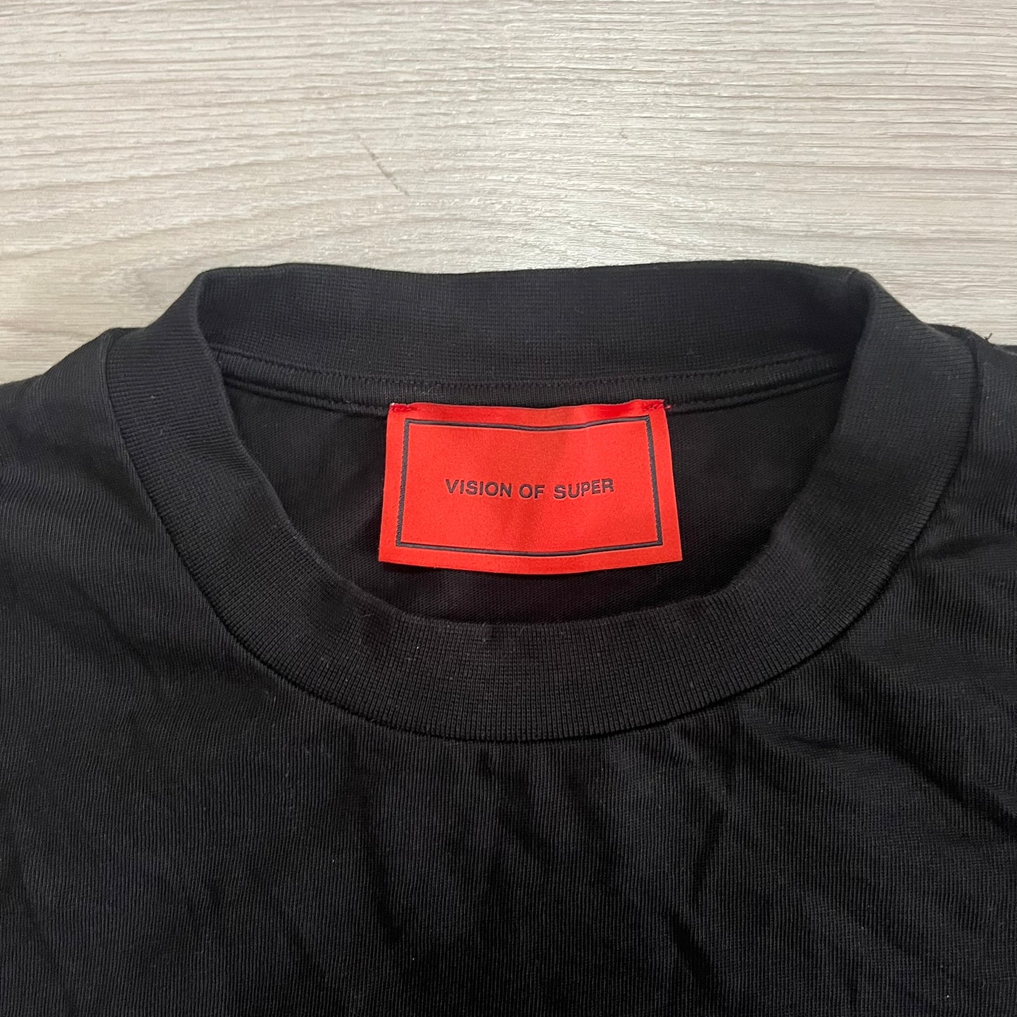 Black shirt with a red label on a wooden surface