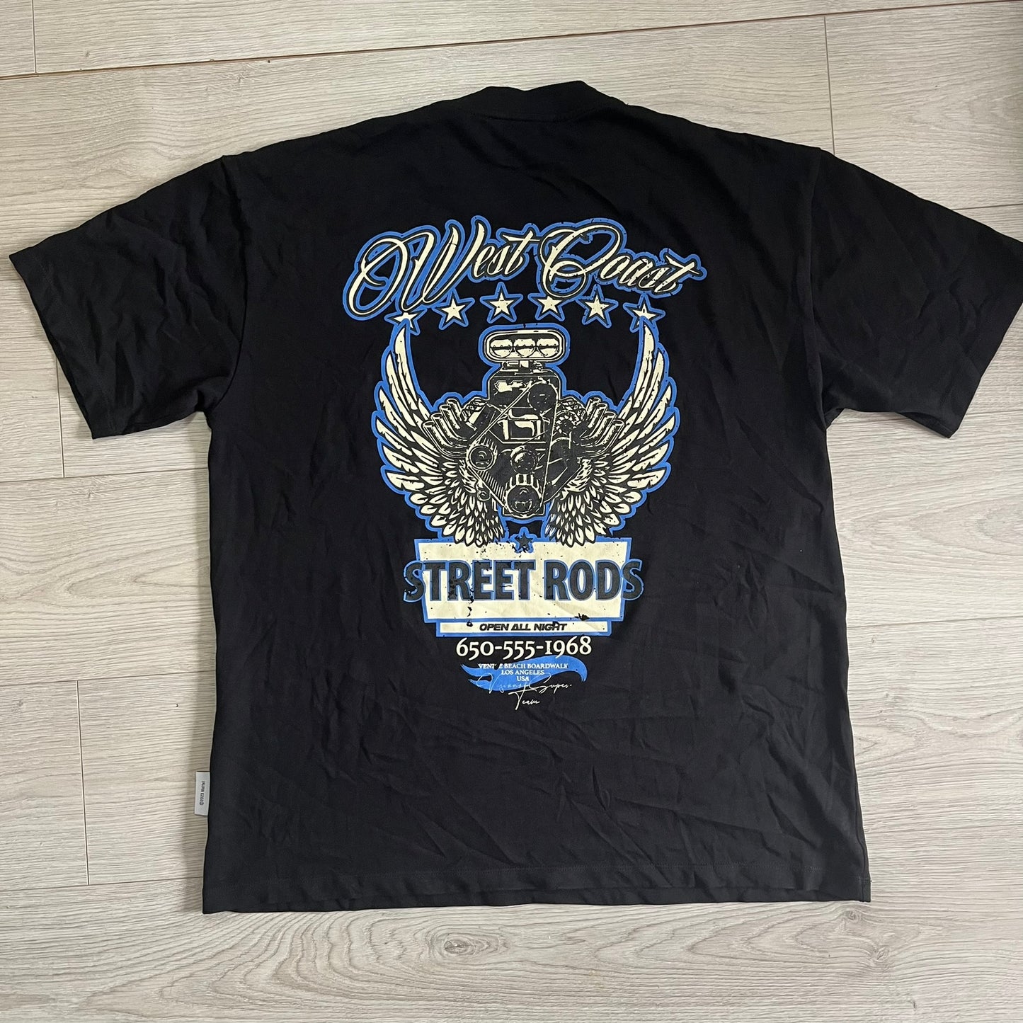 Black t-shirt with blue and white graphic design on a wooden surface