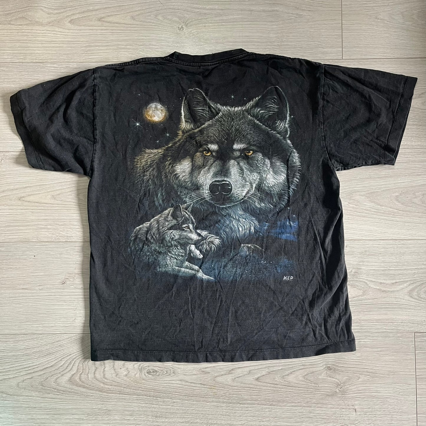 Black t-shirt with a wolf graphic on a wooden surface