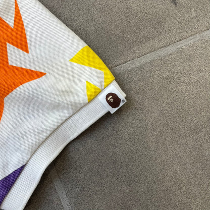 A Bathing Ape 2014 Milo Multicolor Sta Polo is a white, 100% cotton BAPE polo featuring an all-over print of multicolor STA (shooting star) graphics in pink, green, blue, yellow, red (and more), some featuring eyes. It includes branded Bape buttons.