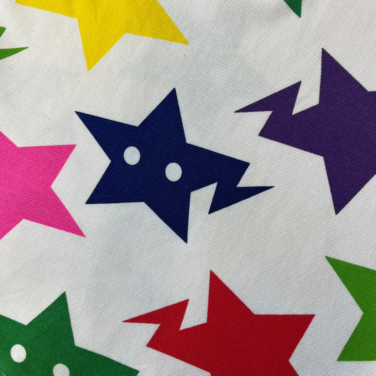A Bathing Ape 2014 Milo Multicolor Sta Polo is a white, 100% cotton BAPE polo featuring an all-over print of multicolor STA (shooting star) graphics in pink, green, blue, yellow, red (and more), some featuring eyes. It includes branded Bape buttons.