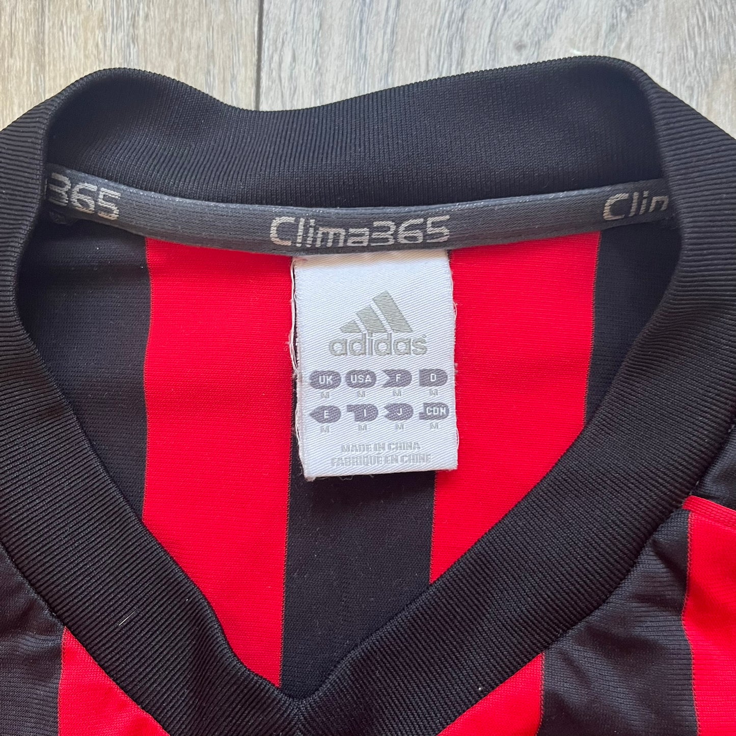 AC Milan Academy x Dolce &amp; Gabbana 2008/09 Home Tee is a black and red striped football shirt with black short sleeves. The chest features AC Milan Academy and Dolce &amp; Gabbana Junior logos on the sides, and a adidas logo in the center. Made with Clima365 technology.
