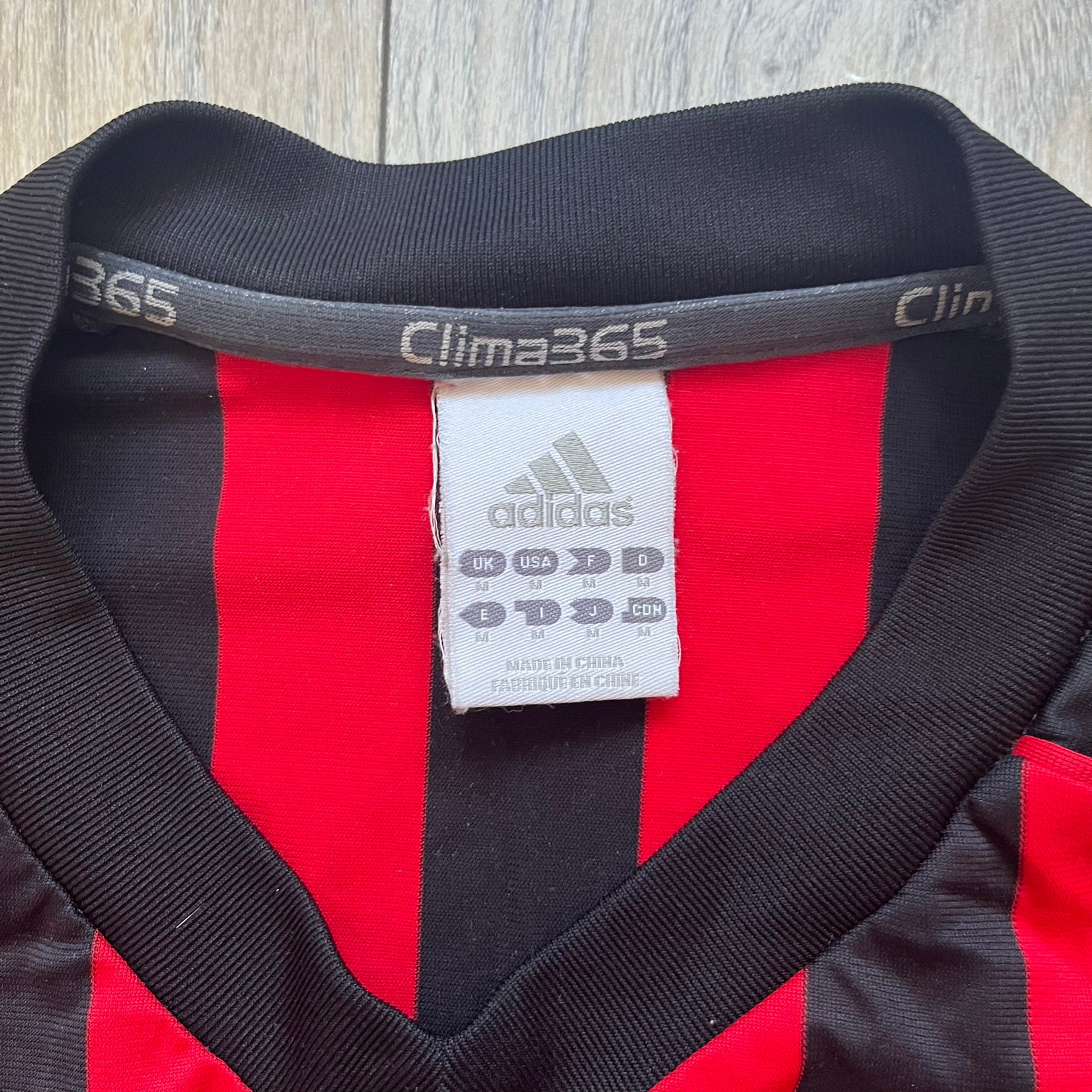 AC Milan Academy x Dolce &amp; Gabbana 2008/09 Home Tee is a black and red striped football shirt with black short sleeves. The chest features AC Milan Academy and Dolce &amp; Gabbana Junior logos on the sides, and a adidas logo in the center. Made with Clima365 technology.
