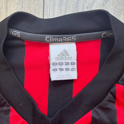 AC Milan Academy x Dolce &amp; Gabbana 2008/09 Home Tee is a black and red striped football shirt with black short sleeves. The chest features AC Milan Academy and Dolce &amp; Gabbana Junior logos on the sides, and a adidas logo in the center. Made with Clima365 technology.
