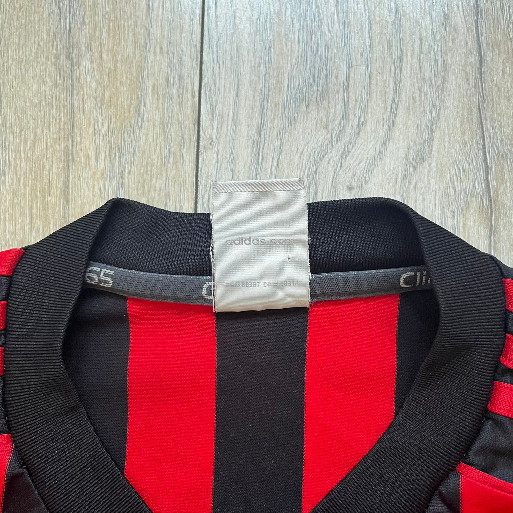 AC Milan Academy x Dolce &amp; Gabbana 2008/09 Home Tee is a black and red striped football shirt with black short sleeves. The chest features AC Milan Academy and Dolce &amp; Gabbana Junior logos on the sides, and a adidas logo in the center. Made with Clima365 technology.
