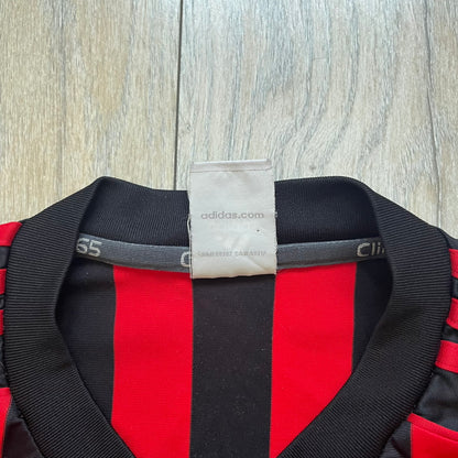 AC Milan Academy x Dolce &amp; Gabbana 2008/09 Home Tee is a black and red striped football shirt with black short sleeves. The chest features AC Milan Academy and Dolce &amp; Gabbana Junior logos on the sides, and a adidas logo in the center. Made with Clima365 technology.
