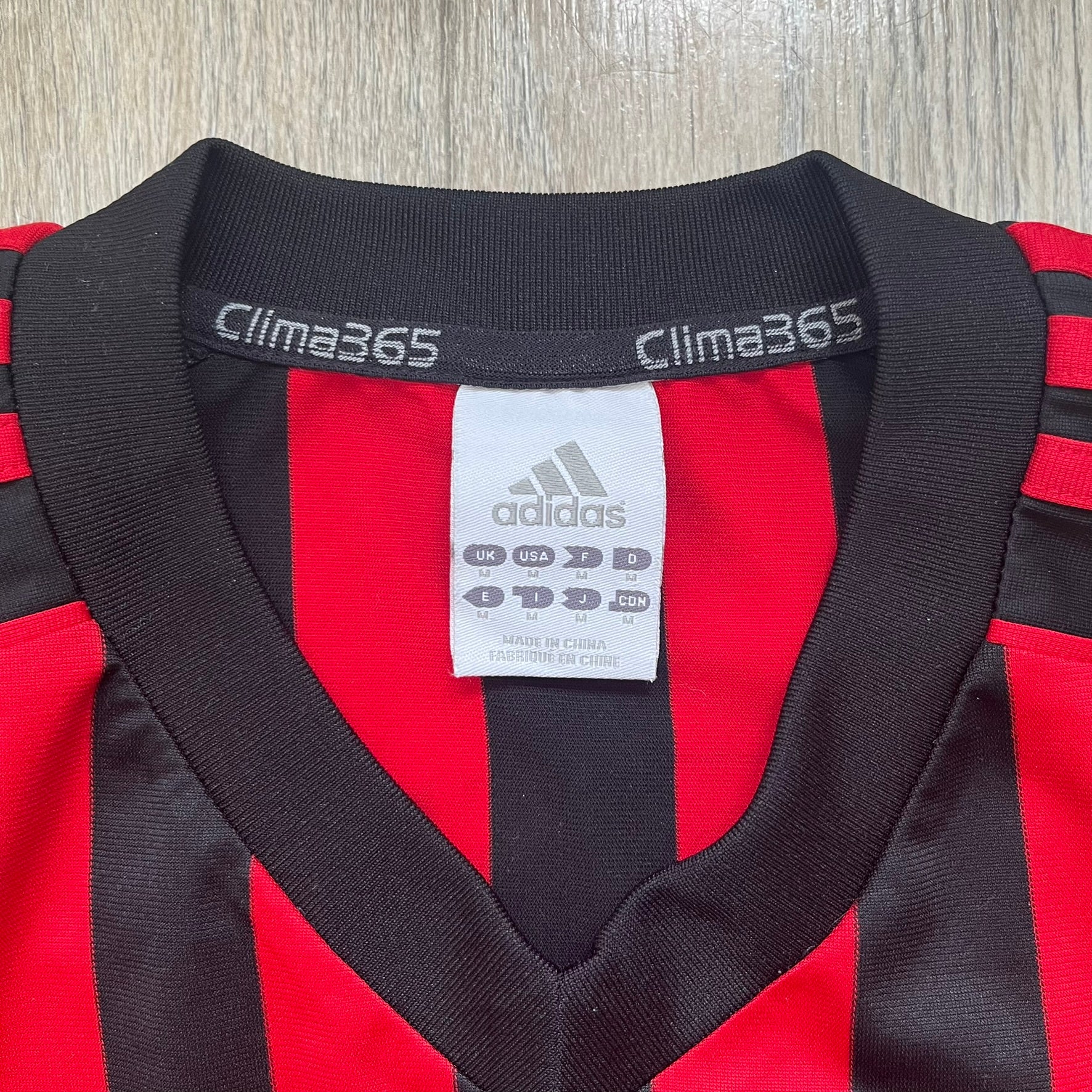 AC Milan Academy x Dolce &amp; Gabbana 2008/09 Home Tee is a black and red striped football shirt with black short sleeves. The chest features AC Milan Academy and Dolce &amp; Gabbana Junior logos on the sides, and a adidas logo in the center. Made with Clima365 technology.