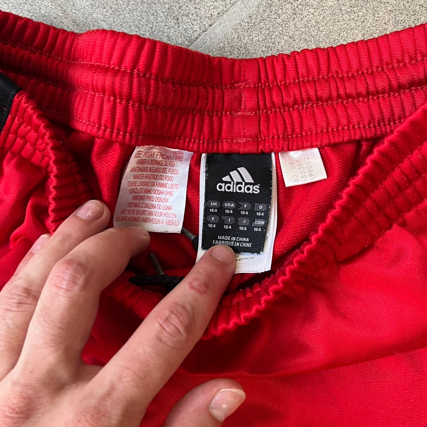 AC Milan x Adidas 2009/10 Junior Track Pants are a black and red junior football track bottoms with 3 black Adidas lines on the side. The right leg features AC Milan logo patch on one side, and Adidas logo embroidered on the left. Made with Climacool technology, it is designed for youth performance wear.