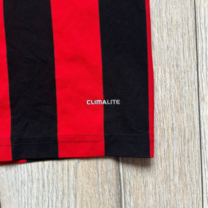 AC Milan x Dolce & Gabbana 2009/10 Home Tee is a black and red striped junior football shirt with black short sleeves. The chest features AC Milan and Adidas logos on the sides, and a D&G Dolce & Gabbana Junior logo in the center. Made with Climacool technology, it is designed for youth performance wear.