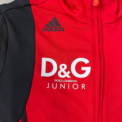 AC Milan x Dolce &amp; Gabbana 2009/10 Track Jacket is a black and red junior football track jacket with asymetrical black and red pattern. The chest features Adidas and D&amp;G Dolce &amp; Gabbana Junior logos on one side, and a AC Milan logo on the left. Made with Climacool technology, it is designed for youth performance wear.