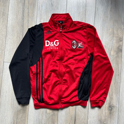 AC Milan x Dolce &amp; Gabbana 2009/10 Track Jacket is a black and red junior football track jacket with asymetrical black and red pattern. The chest features AC Milan and Adidas logos on one side, and a D&amp;G Dolce &amp; Gabbana Junior logo on the left. Made with Climacool technology, it is designed for youth performance wear.