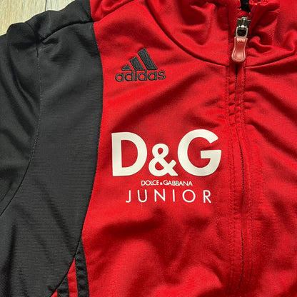 AC Milan x Dolce &amp; Gabbana 2009/10 Track Jacket is a black and red junior football track jacket with asymetrical black and red pattern. The chest features AC Milan and Adidas logos on one side, and a D&amp;G Dolce &amp; Gabbana Junior logo on the left. Made with Climacool technology, it is designed for youth performance wear.