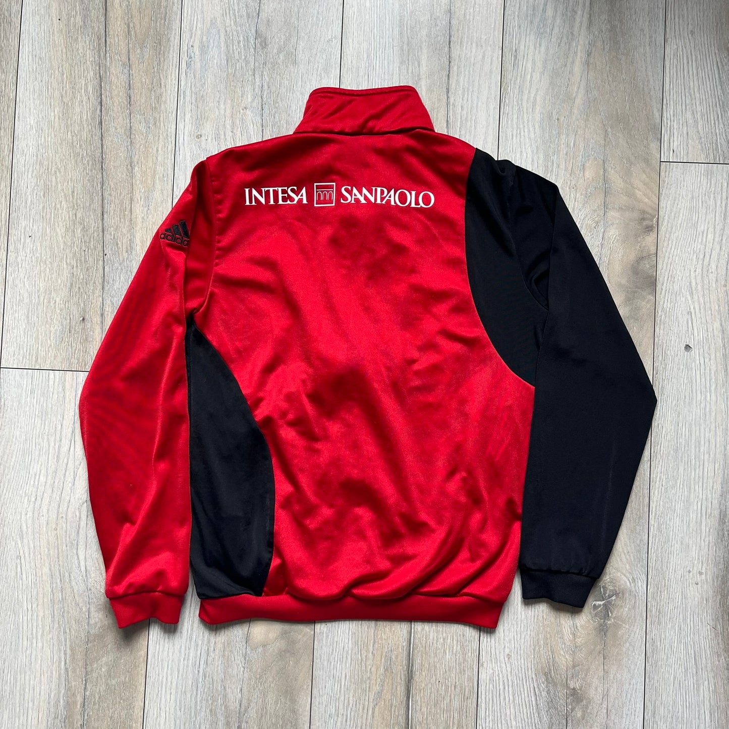 AC Milan x Dolce &amp; Gabbana 2009/10 Track Jacket is a black and red junior football track jacket with asymetrical black and red pattern. The chest features AC Milan and Adidas logos on one side, and a D&amp;G Dolce &amp; Gabbana Junior logo on the left. Made with Climacool technology, it is designed for youth performance wear.