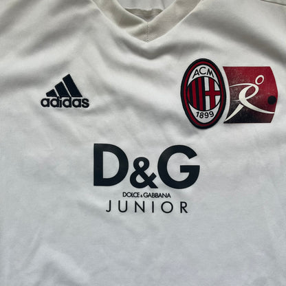 AC Milan x Dolce &amp; Gabbana 2009/10 Training Tee is a white football shirt with red ended short sleeves. The chest features AC Milan and Adidas logos on the sides, and a D&amp;G Dolce &amp; Gabbana Junior logo in the center. Made with Climacool technology, it is designed for performance wear.
