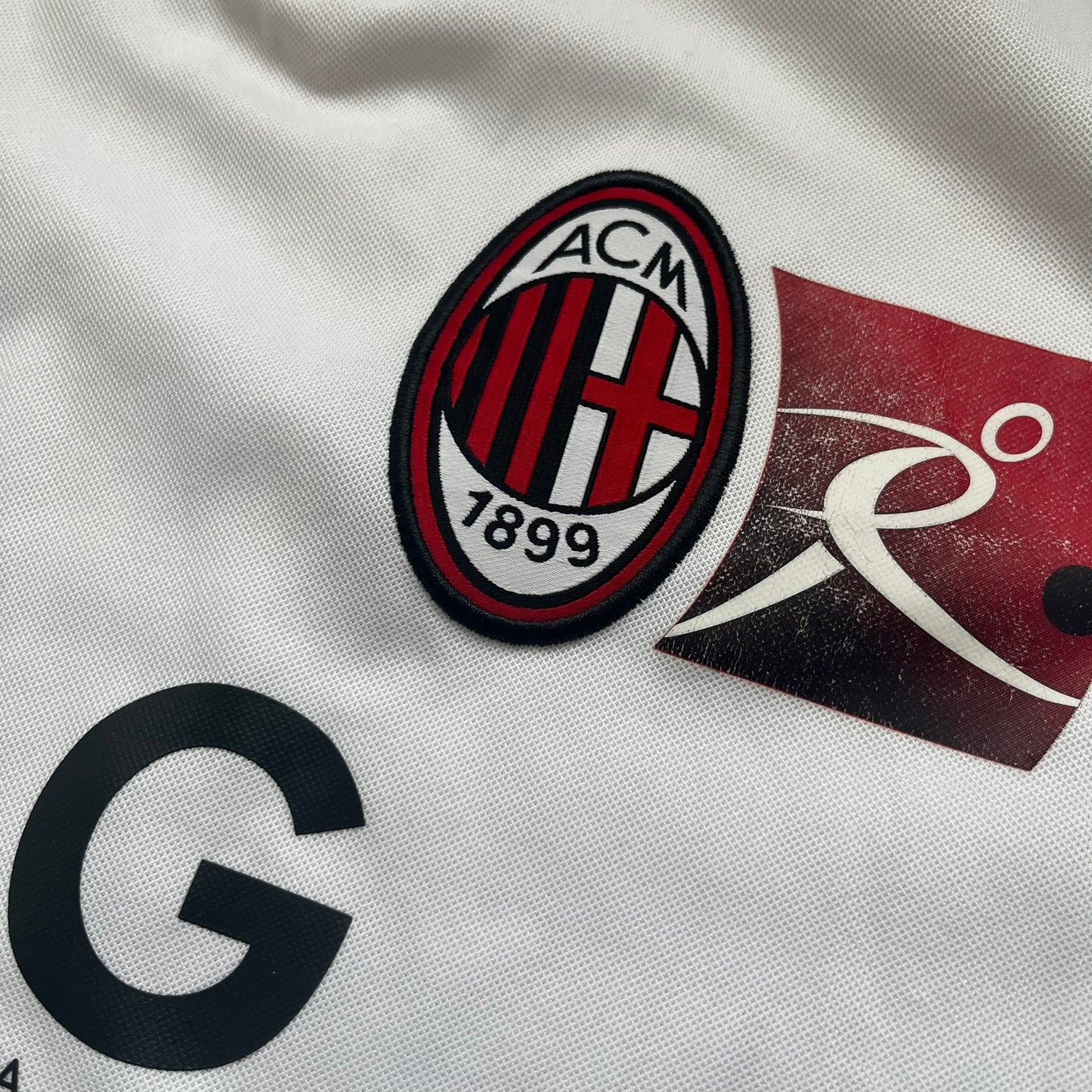 AC Milan x Dolce &amp; Gabbana 2009/10 Training Tee is a white football shirt with red ended short sleeves. The chest features AC Milan and Adidas logos on the sides, and a D&amp;G Dolce &amp; Gabbana Junior logo in the center. Made with Climacool technology, it is designed for performance wear.
