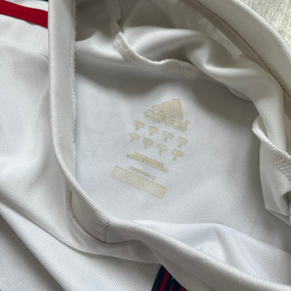 AC Milan x Dolce &amp; Gabbana 2009/10 Training Tee is a white football shirt with red ended short sleeves. The chest features AC Milan and Adidas logos on the sides, and a D&amp;G Dolce &amp; Gabbana Junior logo in the center. Made with Climacool technology, it is designed for performance wear.
