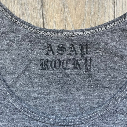 A$AP Rocky 2012 “Peso” Gray Tank Top is a grey sleeveless shirt sold at concerts during the early A$AP Rocky tours. The front features stacked text reading “I be that pretty mother fucker” arranged word-by-word from top to bottom, followed by a line and “ASAP Rocky” beneath. The neckline includes A$AP Rocky branding printed on the tag area.