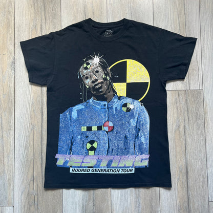 A$AP Rocky 2019 Injured Generation Tour “Crash Dummy” Tee is a black T-shirt released as part of the Injured Generation tour merchandise collection. The front features an illustrated crash dummy version of A$AP Rocky with “TESTING” text printed underneath. The opposite side includes a yellow and black burning TESTING logo graphic. Made in the USA.&nbsp;