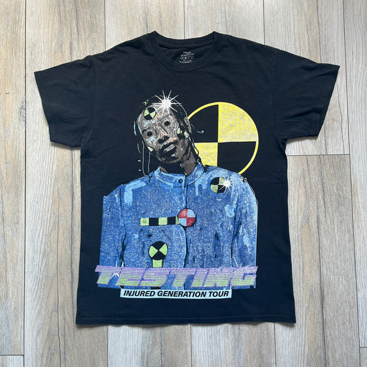A$AP Rocky 2019 Injured Generation Tour “Crash Dummy” Tee is a black T-shirt released as part of the Injured Generation tour merchandise collection. The front features an illustrated crash dummy version of A$AP Rocky with “TESTING” text printed underneath. The opposite side includes a yellow and black burning TESTING logo graphic. Made in the USA.&nbsp;