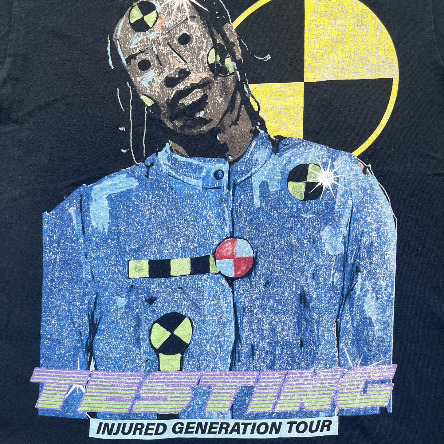 A$AP Rocky 2019 Injured Generation Tour “Crash Dummy” Tee is a black T-shirt released as part of the Injured Generation tour merchandise collection. The front features an illustrated crash dummy version of A$AP Rocky with “TESTING” text printed underneath. The opposite side includes a yellow and black burning TESTING logo graphic. Made in the USA.&nbsp;