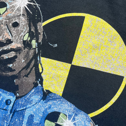 A$AP Rocky 2019 Injured Generation Tour “Crash Dummy” Tee is a black T-shirt released as part of the Injured Generation tour merchandise collection. The front features an illustrated crash dummy version of A$AP Rocky with “TESTING” text printed underneath. The opposite side includes a yellow and black burning TESTING logo graphic. Made in the USA.&nbsp;