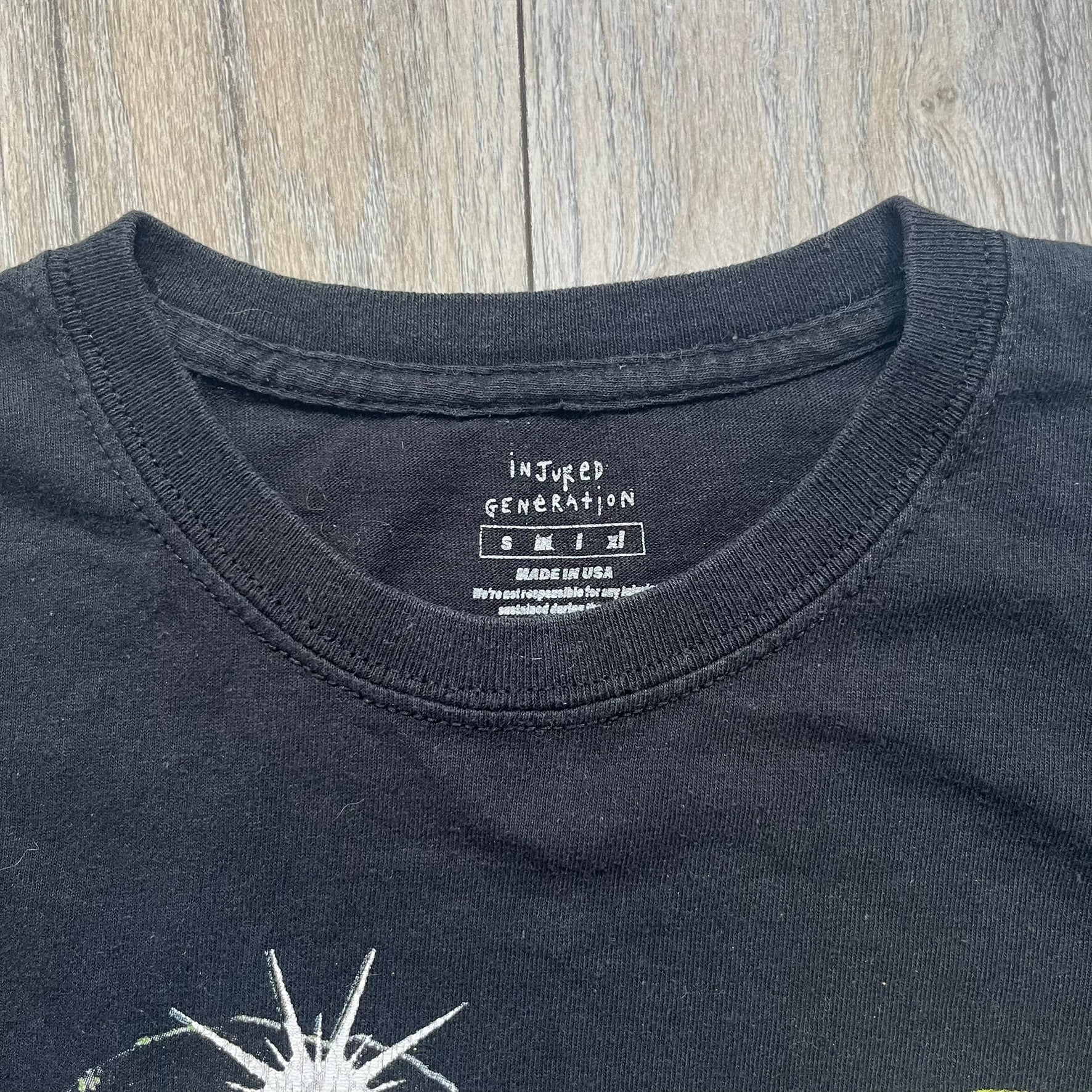 A$AP Rocky 2019 Injured Generation Tour “Crash Dummy” Tee is a black T-shirt released as part of the Injured Generation tour merchandise collection. The front features an illustrated crash dummy version of A$AP Rocky with “TESTING” text printed underneath. The opposite side includes a yellow and black burning TESTING logo graphic. Made in the USA.&nbsp;