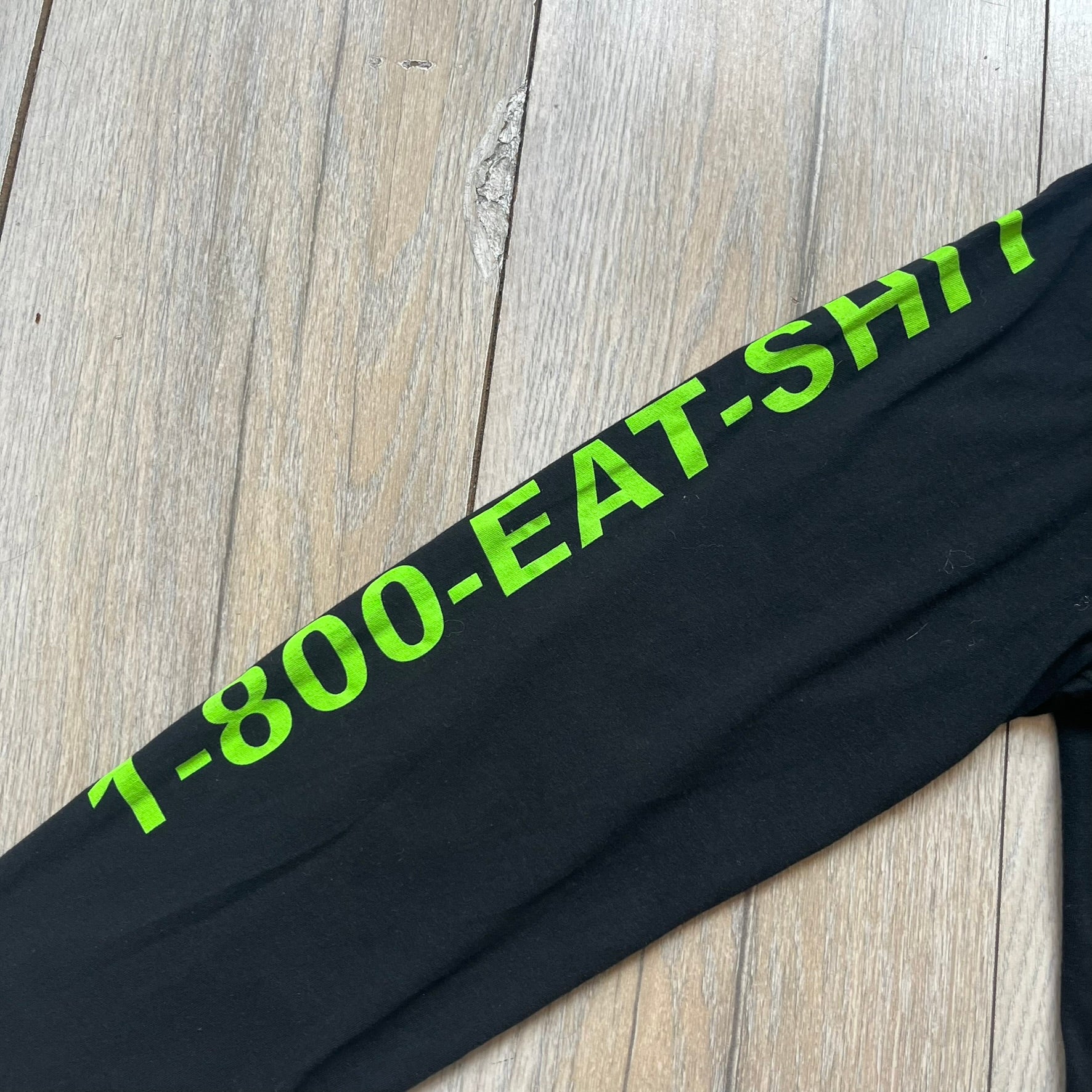 A$AP Rocky 2019 “Injured Generation” Tour “Pickpockets” Longsleeve is a black long-sleeve T-shirt released as part of the Injured Generation tour merchandise collection. The front features a large graphic of A$AP Rocky with green “Warning! Beware of Pickpockets” text. One sleeve includes “1-800-EAT-SHIT” text, while the other features a yellow and green testing-style logo. The back displays large green “Don’t Be a Dummy A$AP Rocky Europe” text layered over a white dummy mask graphic. Made in the USA.