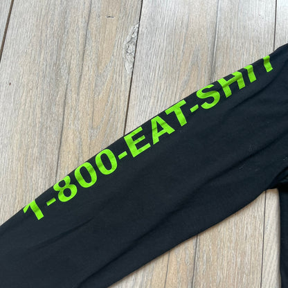 A$AP Rocky 2019 “Injured Generation” Tour “Pickpockets” Longsleeve is a black long-sleeve T-shirt released as part of the Injured Generation tour merchandise collection. The front features a large graphic of A$AP Rocky with green “Warning! Beware of Pickpockets” text. One sleeve includes “1-800-EAT-SHIT” text, while the other features a yellow and green testing-style logo. The back displays large green “Don’t Be a Dummy A$AP Rocky Europe” text layered over a white dummy mask graphic. Made in the USA.