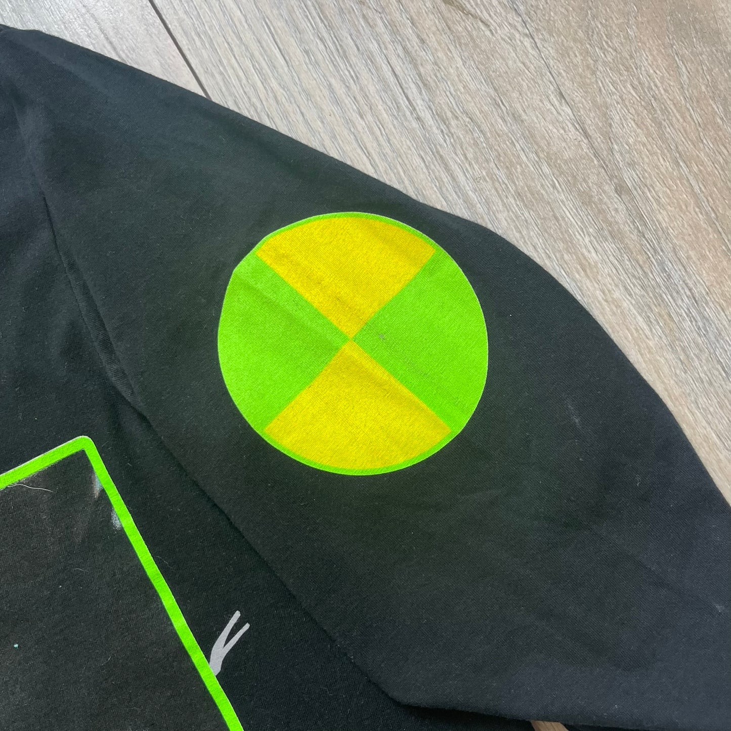 A$AP Rocky 2019 “Injured Generation” Tour “Pickpockets” Longsleeve is a black long-sleeve T-shirt released as part of the Injured Generation tour merchandise collection. The front features a large graphic of A$AP Rocky with green “Warning! Beware of Pickpockets” text. One sleeve includes “1-800-EAT-SHIT” text, while the other features a yellow and green testing-style logo. The back displays large green “Don’t Be a Dummy A$AP Rocky Europe” text layered over a white dummy mask graphic. Made in the USA.