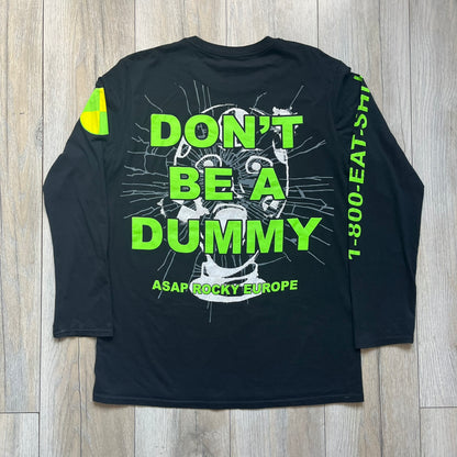 A$AP Rocky 2019 “Injured Generation” Tour “Pickpockets” Longsleeve is a black long-sleeve T-shirt released as part of the Injured Generation tour merchandise collection. The front features a large graphic of A$AP Rocky with green “Warning! Beware of Pickpockets” text. One sleeve includes “1-800-EAT-SHIT” text, while the other features a yellow and green testing-style logo. The back displays large green “Don’t Be a Dummy A$AP Rocky Europe” text layered over a white dummy mask graphic. Made in the USA.