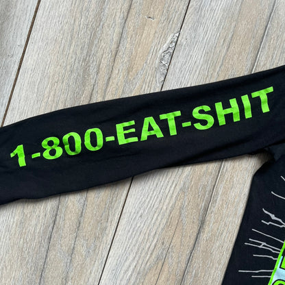 A$AP Rocky 2019 “Injured Generation” Tour “Pickpockets” Longsleeve is a black long-sleeve T-shirt released as part of the Injured Generation tour merchandise collection. The front features a large graphic of A$AP Rocky with green “Warning! Beware of Pickpockets” text. One sleeve includes “1-800-EAT-SHIT” text, while the other features a yellow and green testing-style logo. The back displays large green “Don’t Be a Dummy A$AP Rocky Europe” text layered over a white dummy mask graphic. Made in the USA.