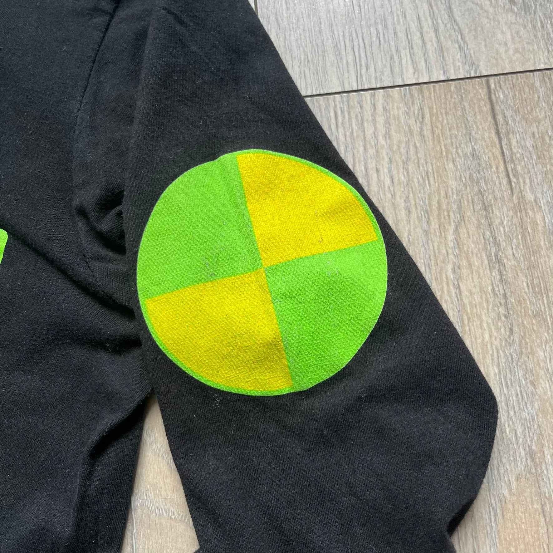 A$AP Rocky 2019 “Injured Generation” Tour “Pickpockets” Longsleeve is a black long-sleeve T-shirt released as part of the Injured Generation tour merchandise collection. The front features a large graphic of A$AP Rocky with green “Warning! Beware of Pickpockets” text. One sleeve includes “1-800-EAT-SHIT” text, while the other features a yellow and green testing-style logo. The back displays large green “Don’t Be a Dummy A$AP Rocky Europe” text layered over a white dummy mask graphic. Made in the USA.