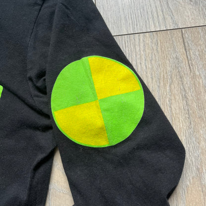 A$AP Rocky 2019 “Injured Generation” Tour “Pickpockets” Longsleeve is a black long-sleeve T-shirt released as part of the Injured Generation tour merchandise collection. The front features a large graphic of A$AP Rocky with green “Warning! Beware of Pickpockets” text. One sleeve includes “1-800-EAT-SHIT” text, while the other features a yellow and green testing-style logo. The back displays large green “Don’t Be a Dummy A$AP Rocky Europe” text layered over a white dummy mask graphic. Made in the USA.