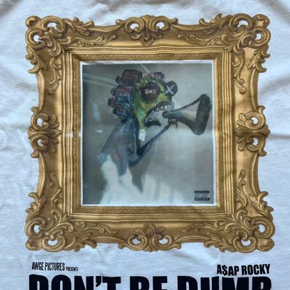 A$AP Rocky “Don’t Be Dumb” GR1M Short Sleeve Tee is a limited release from the AWGE website tied to the rollout of Don’t Be Dumb by A$AP Rocky. The white T-shirt features a green GR1M figure with a megaphone printed on the front with “GRIM” text below. The reverse includes a framed graphic with “Don’t Be Dumb” text, using a lenticular-style vinyl panel that shifts between the GR1M figure and A$AP Rocky in the same pose.