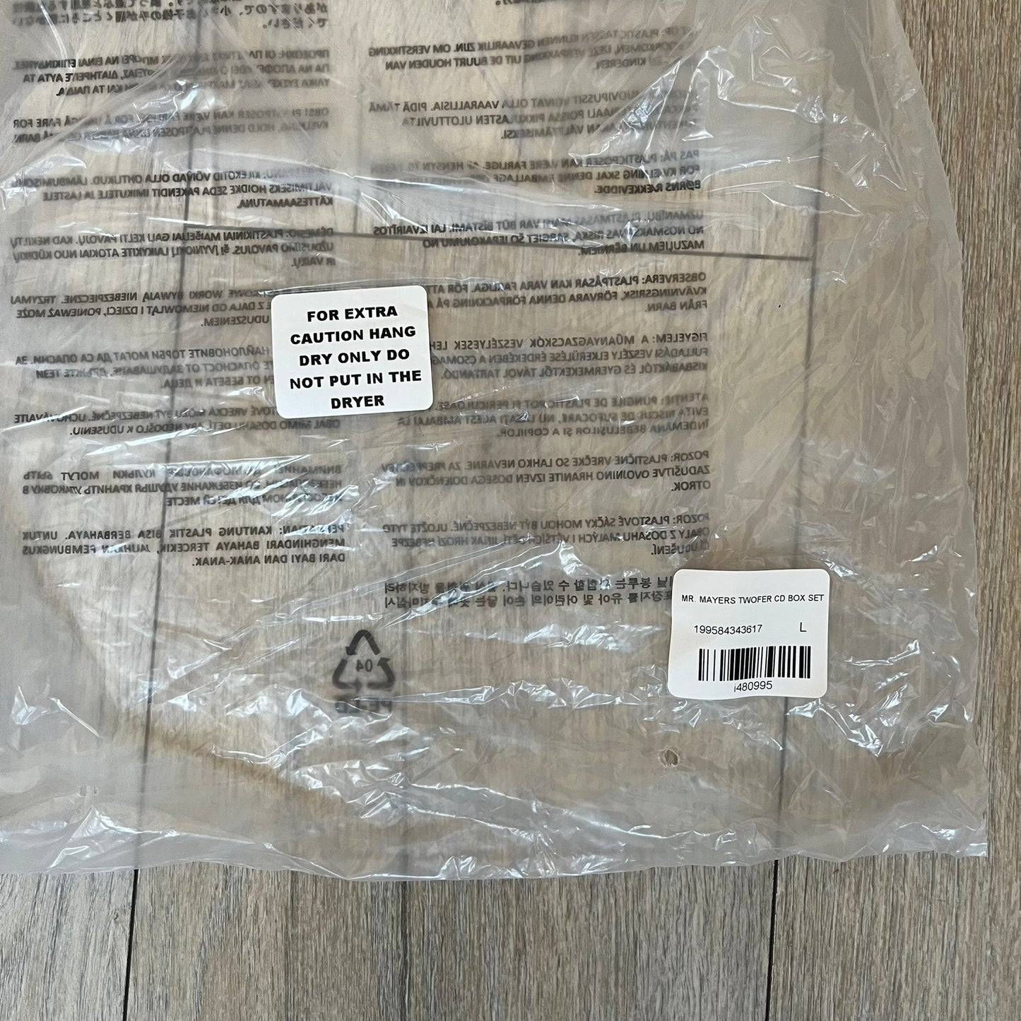 A$AP Rocky “Don’t Be Dumb” Mr Mayers Twofer Longsleeve is a limited release from the AWGE website tied to the rollout of Don’t Be Dumb by A$AP Rocky. The piece features a twofer construction with a black body and white sleeves, with a front graphic of the Mr Mayers figure in a blue trench coat with “Mr Mayers” text and small AWGE logos. The back includes a framed graphic with “Don’t Be Dumb” text, using a lenticular-style vinyl panel that shifts between the Mr Mayers figure and A$AP Rocky in the same outfit