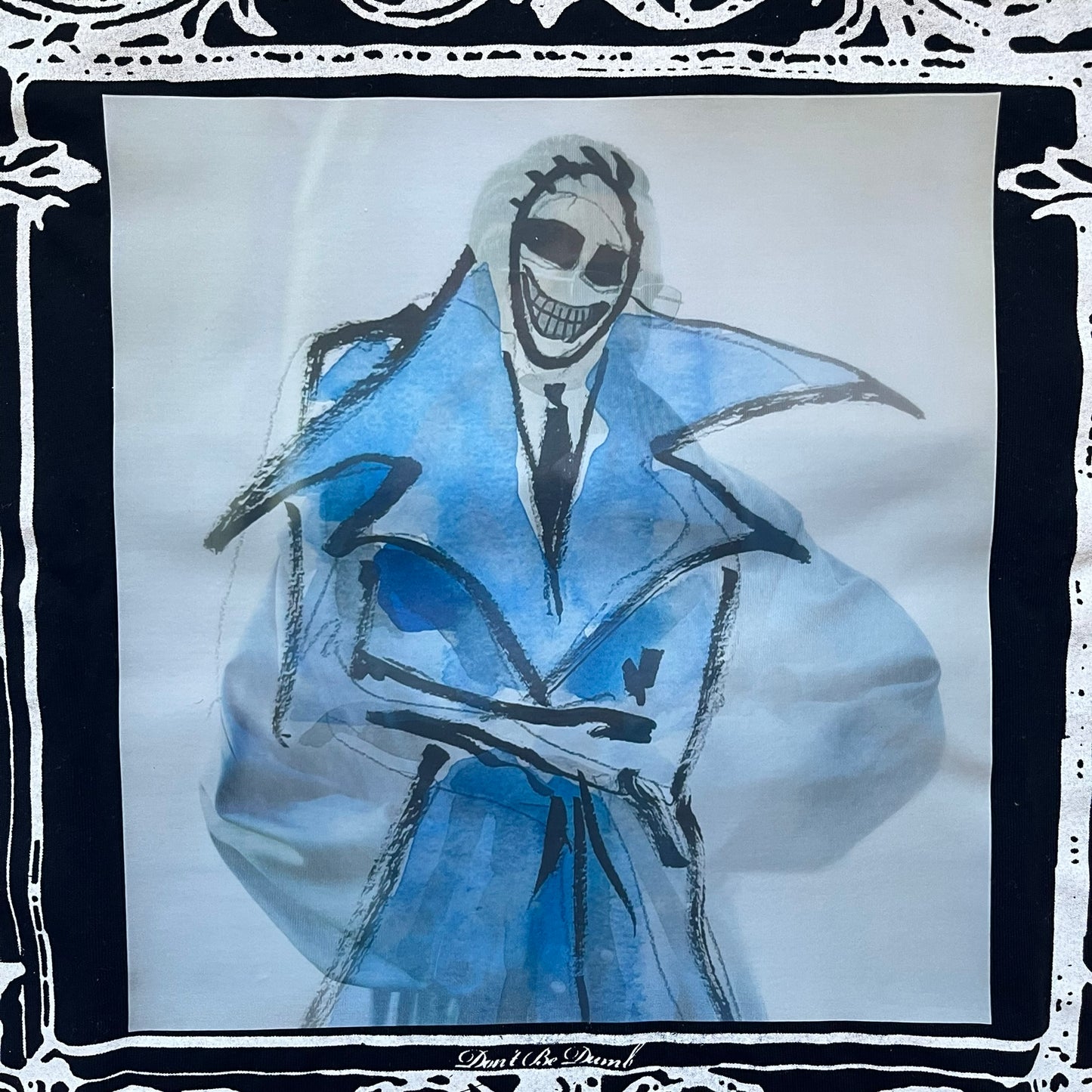 A$AP Rocky “Don’t Be Dumb” Mr Mayers Twofer Longsleeve is a limited release from the AWGE website tied to the rollout of Don’t Be Dumb by A$AP Rocky. The piece features a twofer construction with a black body and white sleeves, with a front graphic of the Mr Mayers figure in a blue trench coat with “Mr Mayers” text and small AWGE logos. The back includes a framed graphic with “Don’t Be Dumb” text, using a lenticular-style vinyl panel that shifts between the Mr Mayers figure and A$AP Rocky in the same outfit