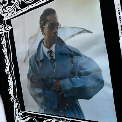 A$AP Rocky “Don’t Be Dumb” Mr Mayers Twofer Longsleeve is a limited release from the AWGE website tied to the rollout of Don’t Be Dumb by A$AP Rocky. The piece features a twofer construction with a black body and white sleeves, with a front graphic of the Mr Mayers figure in a blue trench coat with “Mr Mayers” text and small AWGE logos. The back includes a framed graphic with “Don’t Be Dumb” text, using a lenticular-style vinyl panel that shifts between the Mr Mayers figure and A$AP Rocky in the same outfit