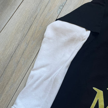 A$AP Rocky “Don’t Be Dumb” Mr Mayers Twofer Longsleeve is a limited release from the AWGE website tied to the rollout of Don’t Be Dumb by A$AP Rocky. The piece features a twofer construction with a black body and white sleeves, with a front graphic of the Mr Mayers figure in a blue trench coat with “Mr Mayers” text and small AWGE logos. The back includes a framed graphic with “Don’t Be Dumb” text, using a lenticular-style vinyl panel that shifts between the Mr Mayers figure and A$AP Rocky in the same outfit