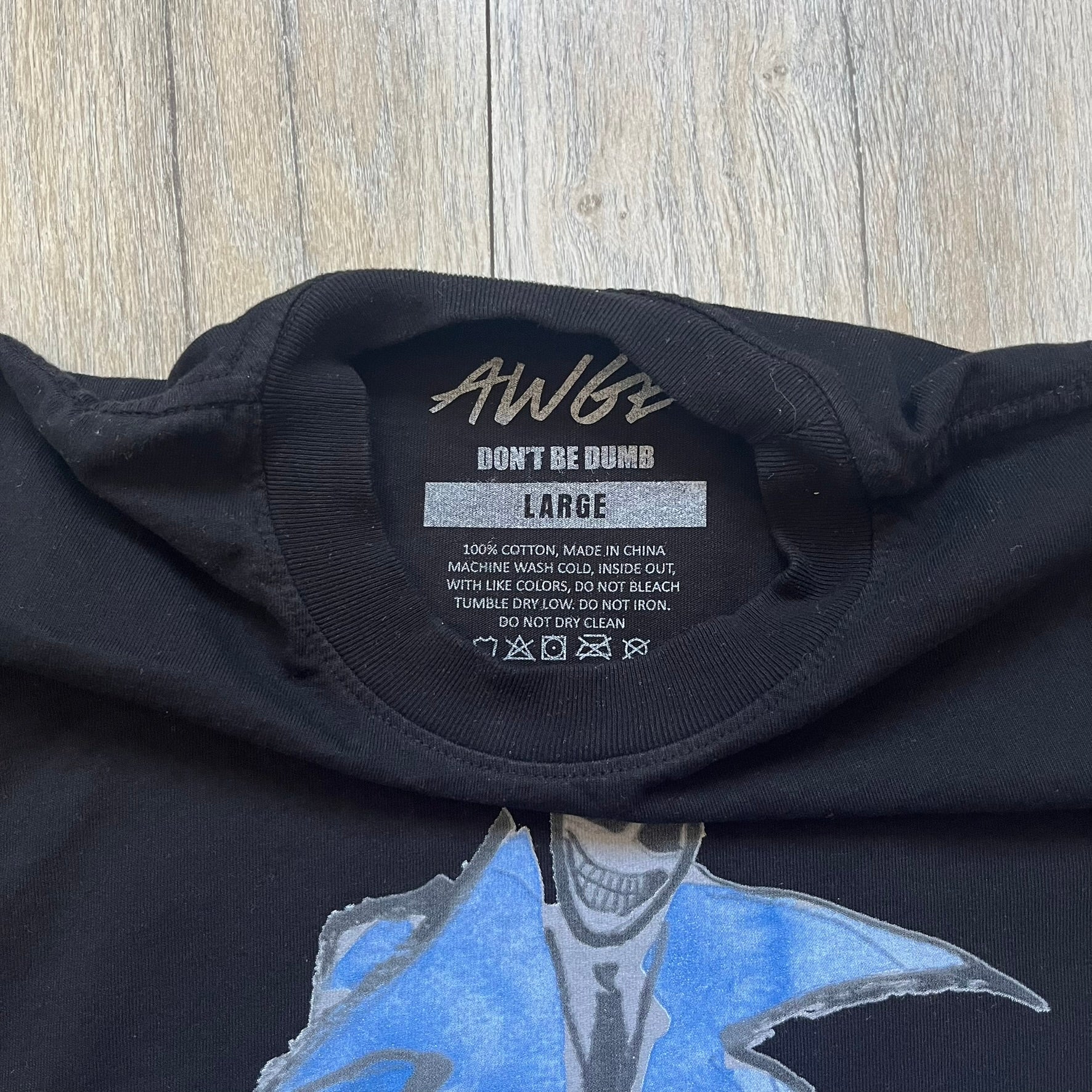 A$AP Rocky “Don’t Be Dumb” Mr Mayers Twofer Longsleeve is a limited release from the AWGE website tied to the rollout of Don’t Be Dumb by A$AP Rocky. The piece features a twofer construction with a black body and white sleeves, with a front graphic of the Mr Mayers figure in a blue trench coat with “Mr Mayers” text and small AWGE logos. The back includes a framed graphic with “Don’t Be Dumb” text, using a lenticular-style vinyl panel that shifts between the Mr Mayers figure and A$AP Rocky in the same outfit