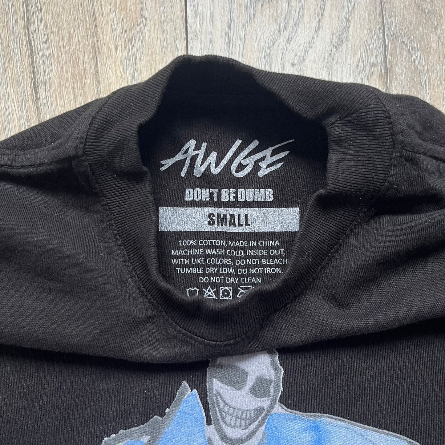 A$AP Rocky “Don’t Be Dumb” Mr Mayers Twofer Longsleeve is a limited release from the AWGE website tied to the rollout of Don’t Be Dumb by A$AP Rocky. The piece features a twofer construction with a black body and white sleeves, with a front graphic of the Mr Mayers figure in a blue trench coat with “Mr Mayers” text and small AWGE logos. The back includes a framed graphic with “Don’t Be Dumb” text, using a lenticular-style vinyl panel that shifts between the Mr Mayers figure and A$AP Rocky in the same outfit
