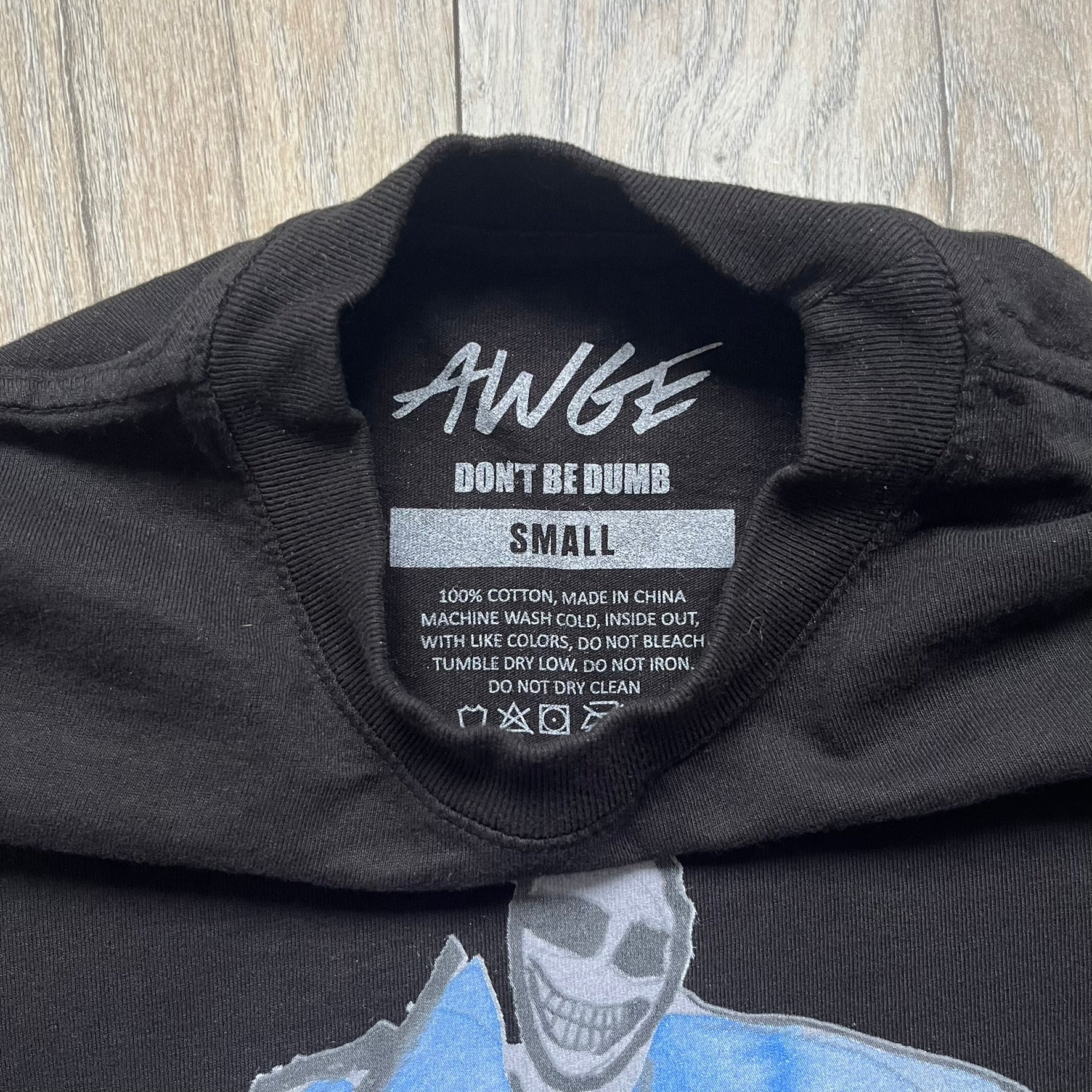 A$AP Rocky “Don’t Be Dumb” Mr Mayers Twofer Longsleeve is a limited release from the AWGE website tied to the rollout of Don’t Be Dumb by A$AP Rocky. The piece features a twofer construction with a black body and white sleeves, with a front graphic of the Mr Mayers figure in a blue trench coat with “Mr Mayers” text and small AWGE logos. The back includes a framed graphic with “Don’t Be Dumb” text, using a lenticular-style vinyl panel that shifts between the Mr Mayers figure and A$AP Rocky in the same outfit