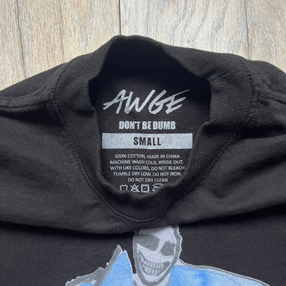 A$AP Rocky “Don’t Be Dumb” Mr Mayers Twofer Longsleeve is a limited release from the AWGE website tied to the rollout of Don’t Be Dumb by A$AP Rocky. The piece features a twofer construction with a black body and white sleeves, with a front graphic of the Mr Mayers figure in a blue trench coat with “Mr Mayers” text and small AWGE logos. The back includes a framed graphic with “Don’t Be Dumb” text, using a lenticular-style vinyl panel that shifts between the Mr Mayers figure and A$AP Rocky in the same outfit