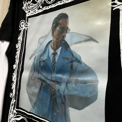 A$AP Rocky “Don’t Be Dumb” Mr Mayers Twofer Longsleeve is a limited release from the AWGE website tied to the rollout of Don’t Be Dumb by A$AP Rocky. The piece features a twofer construction with a black body and white sleeves, with a front graphic of the Mr Mayers figure in a blue trench coat with “Mr Mayers” text and small AWGE logos. The back includes a framed graphic with “Don’t Be Dumb” text, using a lenticular-style vinyl panel that shifts between the Mr Mayers figure and A$AP Rocky in the same outfit