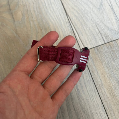 Adidas 2000s Burgundy 10-0117 Digital Watch (model X-003) is a burgundy digital watch with a silver bezel and ergonomic case. It features a burgundy nylon Velcro strap and four side buttons. The design includes three white stripes on the case and a silver Adidas logo button below the screen. The stainless steel back is engraved and marked water resistant up to 3 ATM, with an Adidas logo patch on the strap.