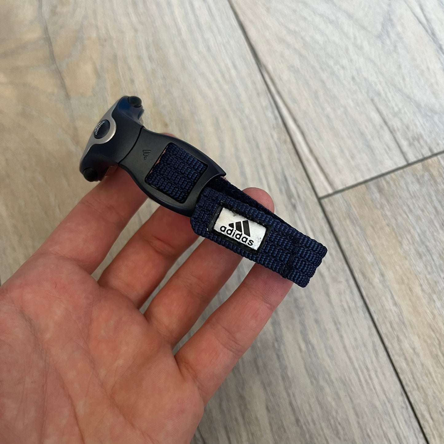 Adidas 2000s Navy 10-0117 Digital Watch (model X-003) is a navy digital watch with a silver bezel and ergonomic case. It features a navy nylon Velcro strap and four side buttons. The design includes three white stripes on the case and a silver Adidas logo button below the screen. The stainless steel back is engraved and marked water resistant up to 3 ATM, with an Adidas logo patch on the strap.