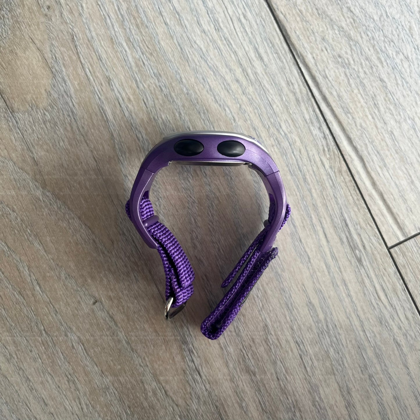 Adidas 2000s Purple 10-0117 Digital Watch (model X-003) is a purple digital watch with a silver bezel and ergonomic case. It features a purple nylon Velcro strap, four side buttons, and a blue-green backlight display showing Adidas logo. The design includes three white stripes on the case and a silver Adidas logo button below the screen. The stainless steel back is engraved and marked water resistant up to 3 ATM, with an Adidas logo patch on the strap
