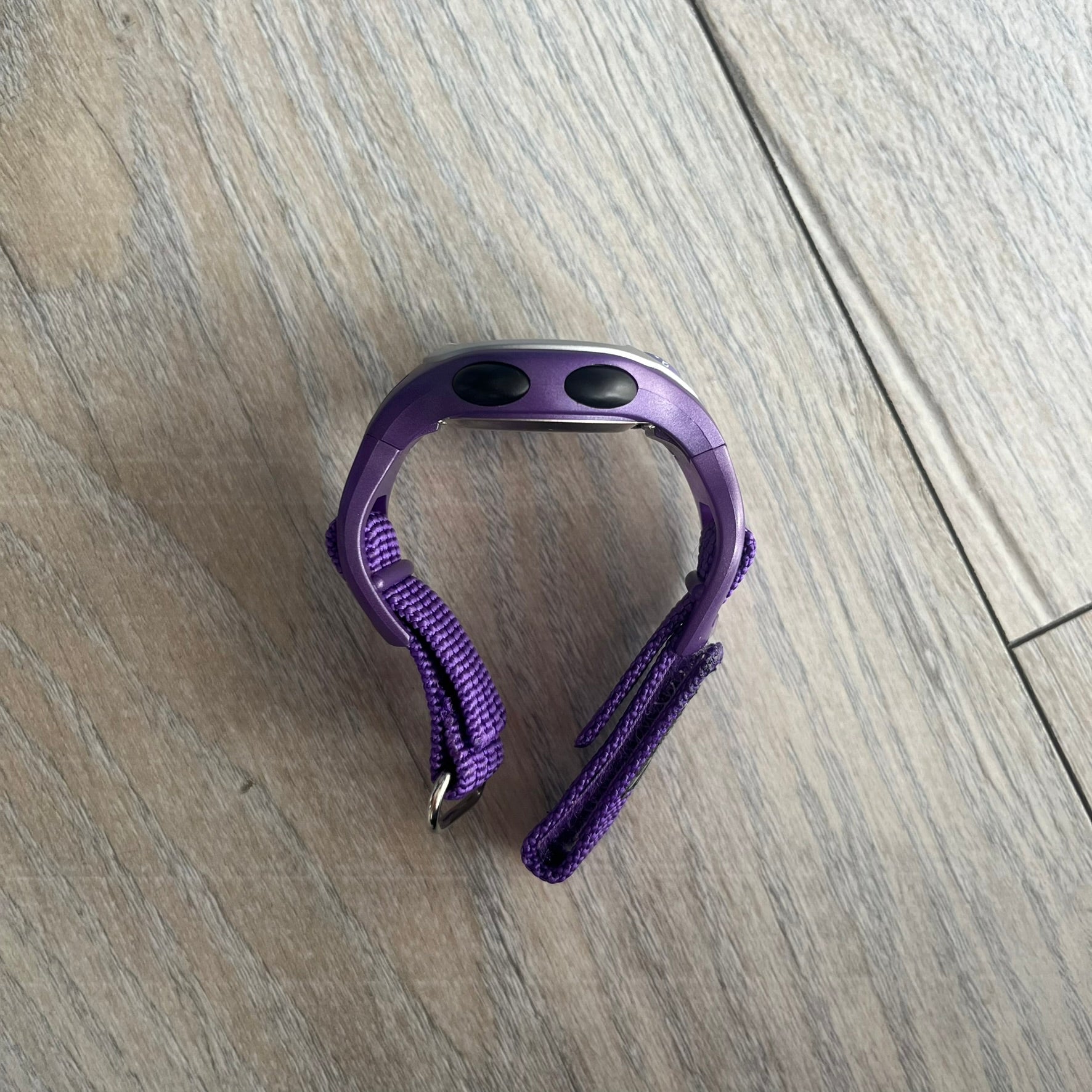 Adidas 2000s Purple 10-0117 Digital Watch (model X-003) is a purple digital watch with a silver bezel and ergonomic case. It features a purple nylon Velcro strap, four side buttons, and a blue-green backlight display showing Adidas logo. The design includes three white stripes on the case and a silver Adidas logo button below the screen. The stainless steel back is engraved and marked water resistant up to 3 ATM, with an Adidas logo patch on the strap