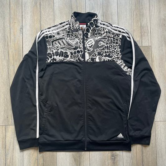Adidas 2009 Doodle Track Jacket is a black track jacket with white Adidas stripes running down the sleeves. The upper chest area on both the front and back is covered in an all-over white doodle and graffiti-style print. It features a full zip closure and a small pocket on the left chest.
